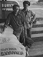 Dos hombres que cargan la harina y una bolsa de harina que dice Minneapolis de Monahan y un camión Pillsbury