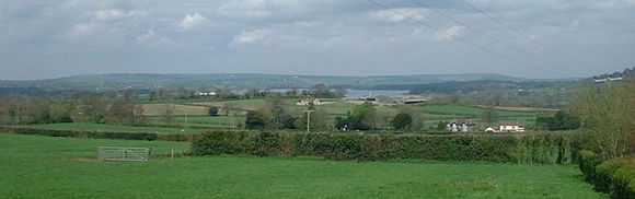 Vista de Chew Valley Lake en la distancia con los campos verdes en primer plano y las montañas en la distancia