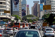 Mirando hacia abajo una carretera muy transitada, que se ladeó a ambos lados por edificios altos, algunos de los cuales están cubiertos en las carteleras del anuncio