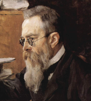 Tête d'un homme aux cheveux grisonnants sombre, des lunettes et une longue barbe