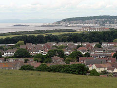 Plusieurs maisons et autres bâtiments autour d'une baie dans laquelle un des projets de Pier. Sur le fond des collines
