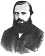 Un homme dans la fin des années 20 ou au début des années 30 avec les cheveux noirs et une barbe touffue, vêtu d'un manteau sombre, chemise et cravate.