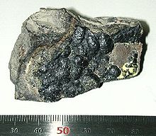 Un gris 5 centimètres pièce brillante de la matière avec une surface rugueuse.