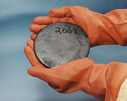 Deux mains dans les gants bruns titulaires d'un disque gris marbré avec un certain nombre 2068 écrit à la main sur elle