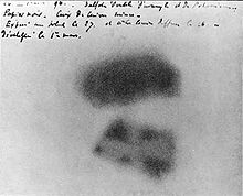 Deux traits noirs floues sur un papier blanc comme fond floue. Il existe une écriture dans la partie supérieure de l'image.