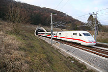 Train blanc électrique avec cheatline rouge émergeant du tunnel dans la campagne