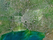 Image satellite montrant une rivière qui coule dans l'océan, avec de grandes zones bâties le long de ses côtés juste avant l'embouchure du fleuve