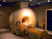 Chambre haute machine médicale jaune-gris avec un trou de taille humaine dans le milieu et une civière directement en face de celui-ci