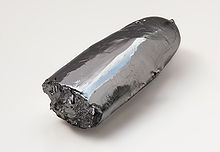 Une barre irrégulière de métal argenté brillant. Une extrémité est rugueuse, comme si cassé, tandis que l'autre extrémité en forme de cigare est relativement lisse.