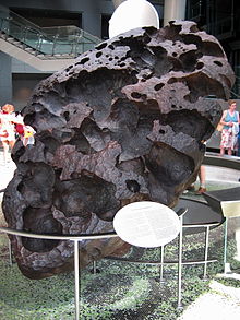 Un gros œuf noir) rocher en forme de la structure poreuse debout sur son sommet, inclinée.