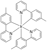 Formule squelettique d'un composé chimique avec un atome d'iridium en son centre, relié à six anneaux de benzol. Les anneaux sont reliés par paires à l'autre.