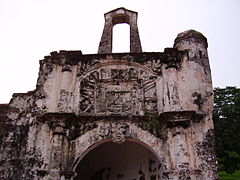 Stained ruine d'un bâtiment en pierre, montrant un arc central, flanqué de deux colonnes, avec un relief de pierre au-dessus de l'arc, également flanqué de deux colonnes, et un deuxième arche autoportante perché sur le haut de la ruine.