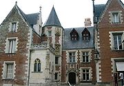 Photo d'une grande maison médiévale, construit en briques avec de nombreuses fenêtres et des pignons et une tour circulaire avec un toit conique.