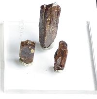 Três coluna em forma de cristais castanhos em um fundo branco