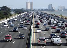 Olhando para baixo uma linha reta ocupado ten-lane rodovia corrida ao longo de uma linha costeira. No fundo são um dos poucos edifícios de vários andares.
