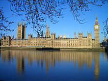 As casas do parlamento em Londres, visto através do rio, um grande edifício de estilo gótico vitoriano, com duas grandes torres e muitos pináculos