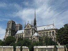 Notre Dame, Paris, é uma catedral gótica grande com torres em uma extremidade e uma pequena torre subindo do centro do telhado.