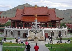 A fotografia de um grande edifício Mongolian de telhado vermelho, com uma árvore metálica elaborado na frente dele, cerca de 30 pés de altura