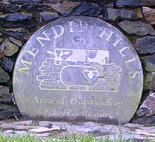 Exposto placa circular azul com o logotipo de Hills Área de impressionante beleza natural do Mendip