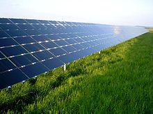 Os painéis solares, em ângulo em cerca de 30 graus, refletem o céu azul de cima de um campo gramado.