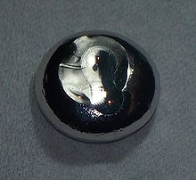 Uma gota achatada de substância cinza escuro.