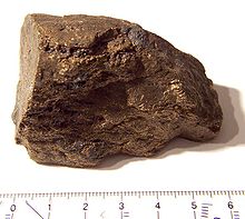 Um bloco marrom de forma irregular e superfície, cerca de 6 cm de tamanho.