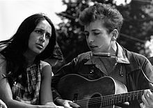 Dylan está sentado, cantando e tocando violão. Sentado à sua direita é uma mulher olhando para cima e cantar com ele.