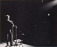 Um foco de luz brilha sobre Dylan como ele executa em palco.